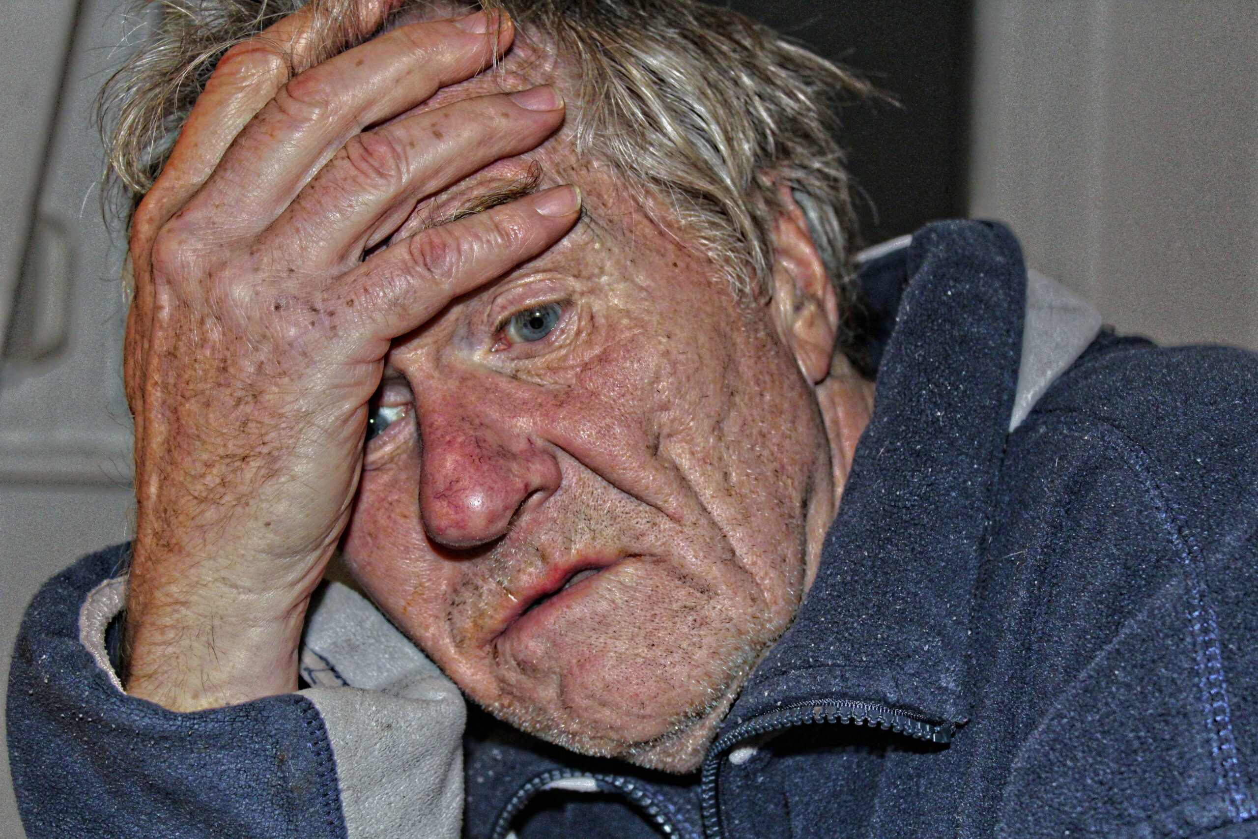 An elderly man with a thoughtful expression sits in a dementia care home, reflecting the challenges of old age and Alzheimer's.