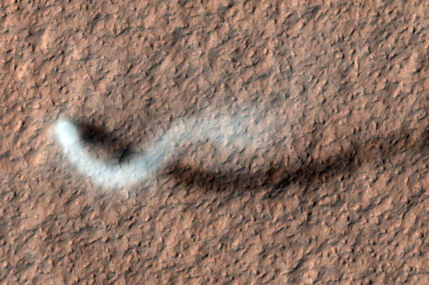Tall dust devil twisting across the Martian surface, captured by Mars Reconnaissance Orbiter.