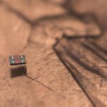 A microscopic autonomous robot resting on a U.S. penny, showing its tiny size relative to everyday objects