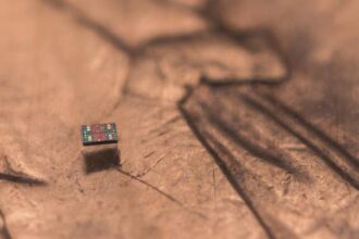 A microscopic autonomous robot resting on a U.S. penny, showing its tiny size relative to everyday objects
