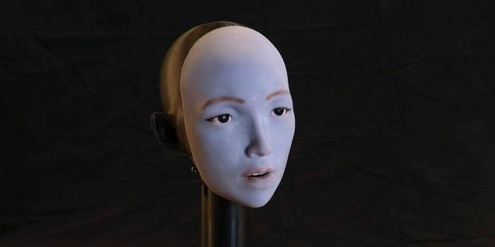 Humanoid robot with flexible facial skin and motors, performing lip movements to match speech and singing.