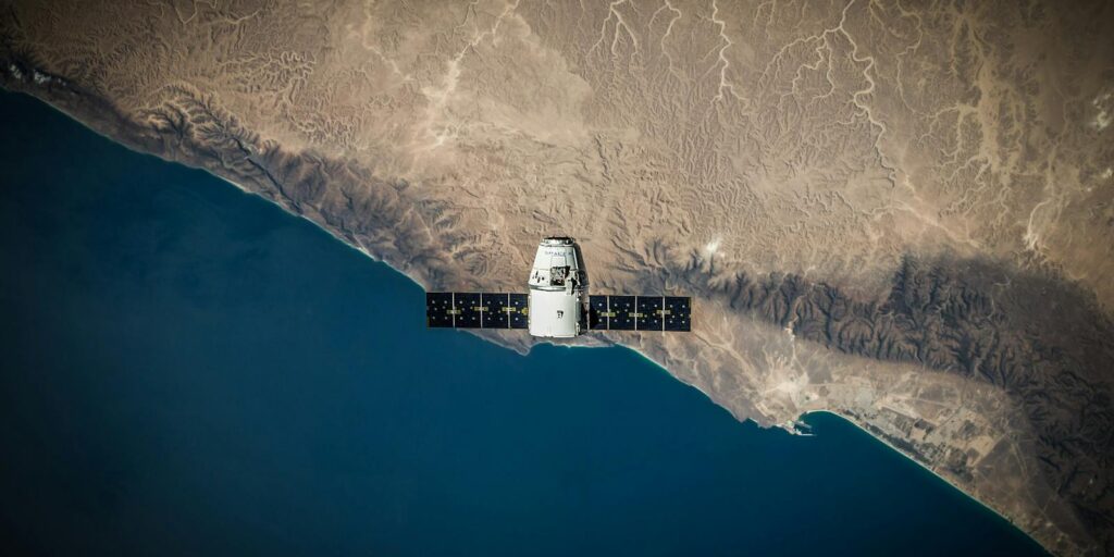 A satellite hovering above Earth's coastline, captured from space.
